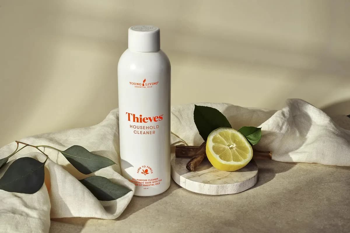 Flasche Thieves Household Cleaner neben einer aufgeschnittenen Zitrone und einem gefalteten Leinentuch im warmen Studiolicht.