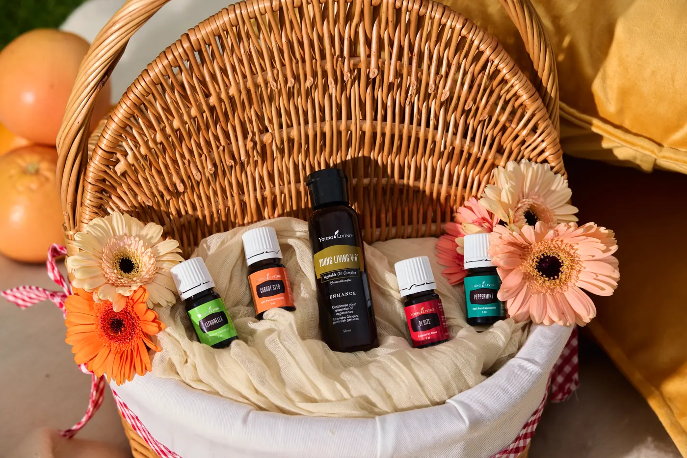 Ätherische Öle von Young Living in einem Picknickkorb mit Sommerblumen